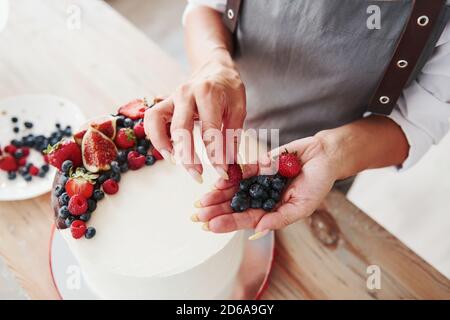 Close up view of woman that puts cherries on the sweet pie Stock Photo