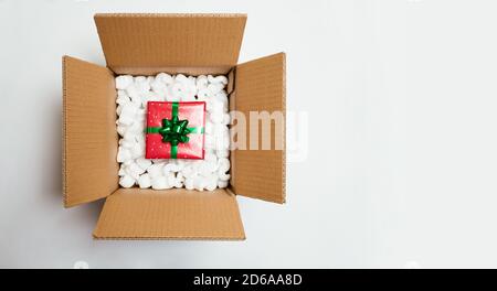 Christmas gift in a cardboard box with foam cushion isolated on white. Christmas home delivery or shipping concept. Top view Stock Photo