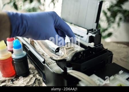 Refilling printer cartridges with multi-colored ink. Background Stock Photo