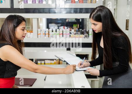 A manager at a beauty salon reception explains her services to a beautiful young woman, business concept, customer service. Stock Photo