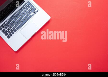 Laptop computer on bright red color background. Open laptop metal silver color top view. Home office concept, copy space, template Stock Photo