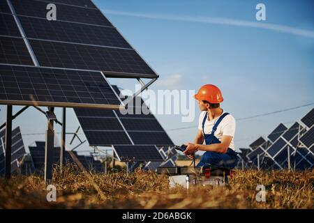 Using laptop. Male worker in blue uniform outdoors with solar batteries at sunny day Stock Photo