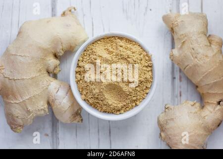 Grounded ginger and ginger root on white wooden surface. Stock Photo