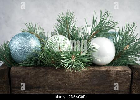 Christmas balls and pine branches in a wooden box on a gray concrete background. Stock Photo