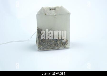 White dry tea bag on a gray background. One rectangular tea bag close-up. Herbal and black tea bags. Stock Photo