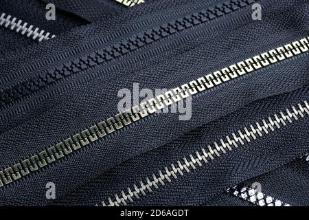 Zipper roll plastic and metal top view. Different types of zippers for making clothes and bags background. Black zippers for clothes for garment produ Stock Photo