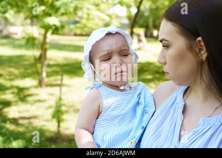 A baby is upset. Mother is looking at disappointed daughter. Stock Photo