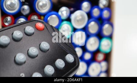 TV remote control with disposable AAA and AA alkaline batteries. Battery replacement, spare parts. Recycling concept. Lots of batteries Stock Photo