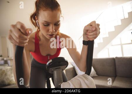 Woman exercising on stationary bike at home Stock Photo