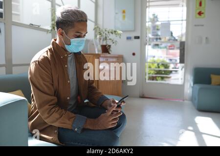 Man wearing face mask using smartphone Stock Photo