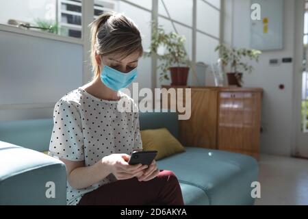Woman wearing face mask using smartphone Stock Photo