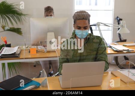 Man wearing face mask using laptop at office Stock Photo