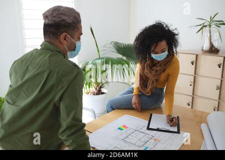 Woman wearing face mask taking notes in office Stock Photo
