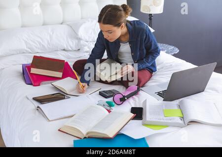 Woman taking notes while sitting on bed at home Stock Photo