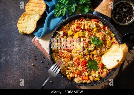 Turkish cuisine. Menemen Scrambled eggs in a cast iron frying pan on a stone countertop. Top view flat lay background. Copy space. Stock Photo