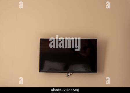 Big TV screen on beige wall, home cinema system Stock Photo
