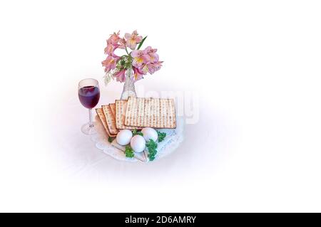 Jewish Passover (Pesah) holiday celebration concept, matzo, eggs, parsley, wine, and flowers, isolated on white background with copy space. Stock Photo