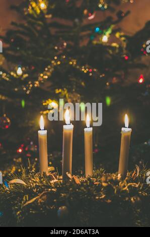 4 candle advent wreath with glowing christmas tree background Stock Photo