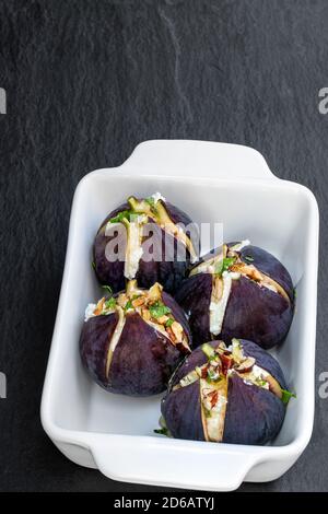 Figs  with goat cheese and walnuts with honey on black stone background Stock Photo