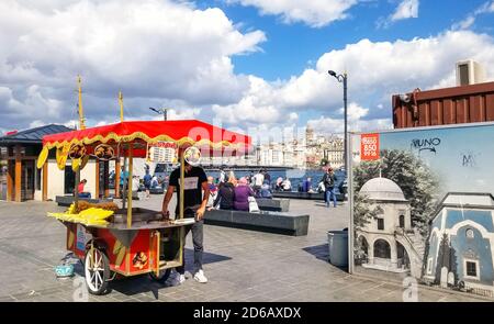 A street food vendor selling corn on the cob near the Galata Bridge with the Bosphorus River and Tower in view. Stock Photo