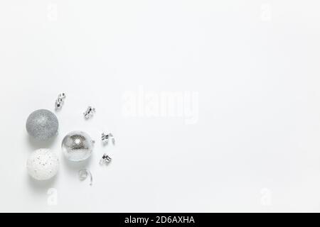 Festive composition. Three silver Christmas balls and tinsel on white background, copy space. Concept preparing gifts, packaging, tree decoration. Hor Stock Photo