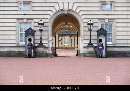 Entrance of Buckingham Palace - England - United Kingdom - with (unrecognizable) Welsh Guards in blue uniform standing guard and seethrough the gate t Stock Photo
