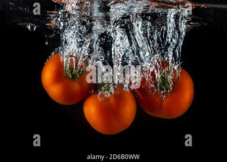 Tomatoes splashing in water on a black background Stock Photo