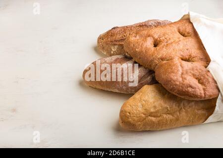 Reusable textile grocery bag with fresh baked bread on a gray concrete background. side view, copy space. zero waste concept. Stock Photo