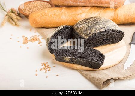 Sliced black bread with different kinds of fresh baked bread on a white wooden background. side view, close up, copy space. Stock Photo
