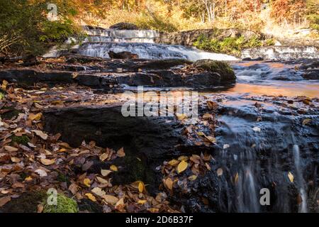 Peak fall foliage surrounds beautiful cascading Shohola Falls on an Autumn morning in the Pennsylvania Poconos Stock Photo