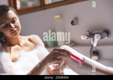 Woman shaving her legs in bathtub Stock Photo