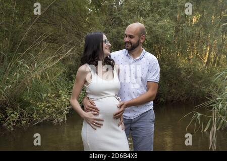 Cheerful Caucasian couple on maternity shoot in a river Stock Photo