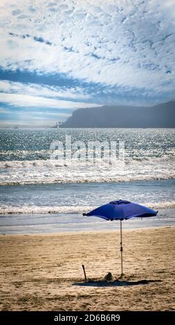 A lone umbrella sits on a beach in Coronado, CA with Point Loma in the background. Stock Photo