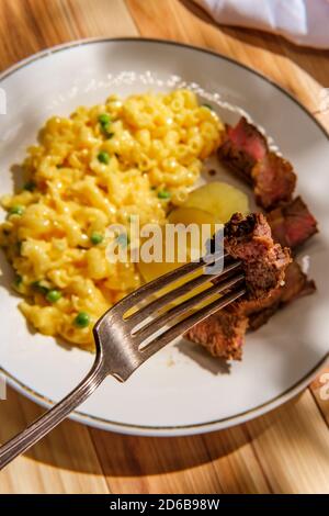 Steak and potatoes with macaroni and cheese with green peas Stock Photo