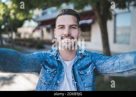 Portrait of young handsome man wearing casual clothes and taking a selfie outdoors in the street. Stock Photo
