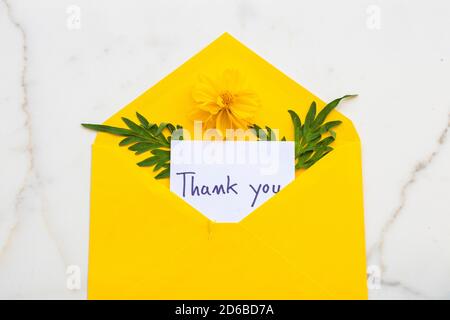 thank you message card handwriting in envelope and yellow flowers cosmos arrangement flat lay postcard style on background white Stock Photo