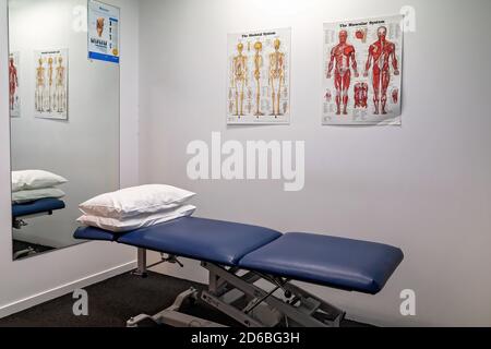 Mackay, Queensland, Australia - February 2020: Adjustable patient treatment bed with pillows in physiotherapist clinic with wall charts Stock Photo
