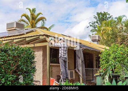 Townsville, Queensland, Australia - June 2020: Man standing on trestles sanding roof rafters of residential house Stock Photo