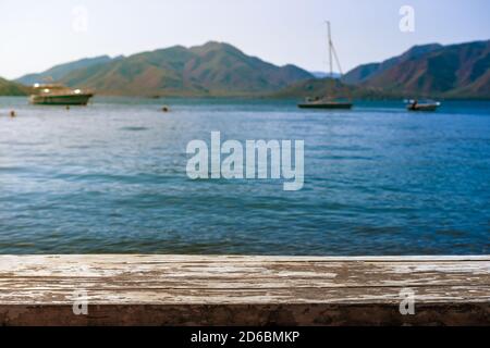 Empty Wooden desk With Beautiful Blue Sea Background For Montage Products Display. Empty wooden table top with blurred sea, sky and mountain backgroun Stock Photo