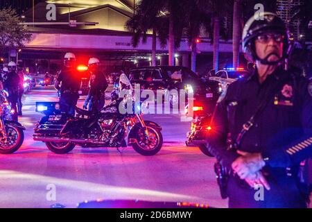 President Donald Trump is visible through the window of the car he is riding in his motorcade as it pulls onto Biscayne Boulevard and makes it's way to the Pérez Art Museum Miami where he held a town hall in Miami.Demonstrators both for and against President Trump gathered in downtown Miami tonight where the president held a town hall meeting with NBC News where the Presidential Debate was to be held before it was canceled. The president scheduled this town hall to compete with Joe Biden's town hall with ABC news in Pennsylvania and their competing events took place in lieu of the canceled Pre Stock Photo