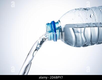 Close up of water coming out of a plastic bottle on a white background Stock Photo