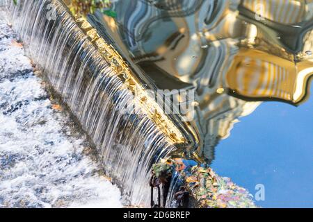 Classicistic house facade mirrored in a brook with a small waterfall Stock Photo