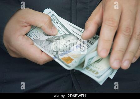 A male employee counts the salary in dollars, close-up. Cash for pocket expenses. Tips in 100 bills. counting. money with hands Stock Photo