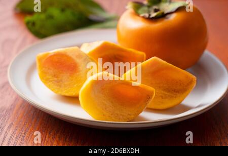 Cut Japanese persimmons on a plate. Japanese style image. Stock Photo
