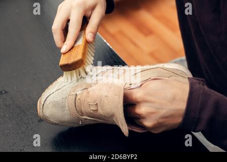 Cleaning suede sneakers. A worker in a shoe workshop cleans a pile of shoes. Stock Photo