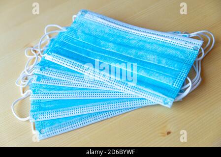 Blue surgical masks, placed on wooden surface Stock Photo