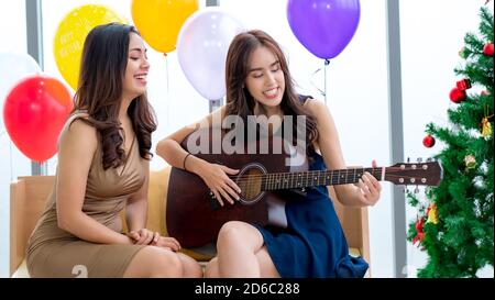 Asian women play guitar and sing for Christmas Stock Photo