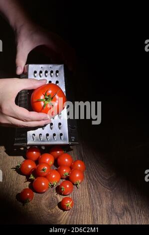Conceptual A Man Hands Grinds Tomato On A Grater Stock Photo