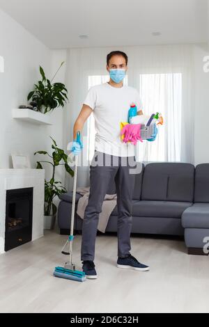 cleaning, health and hygiene concept - indian man wearing protective medical mask for protection from virus disease in gloves with detergent and mop