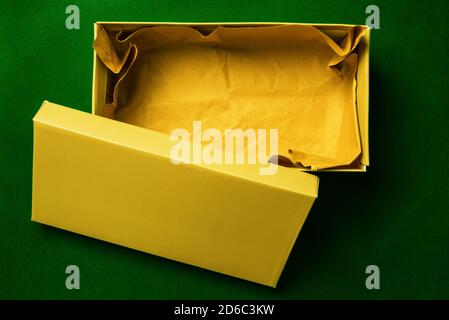 Yellow box on a green background. Color cardboard packaging for shipment of the goods. Cardboard box for shoes or gift. Top view, flat layout Stock Photo